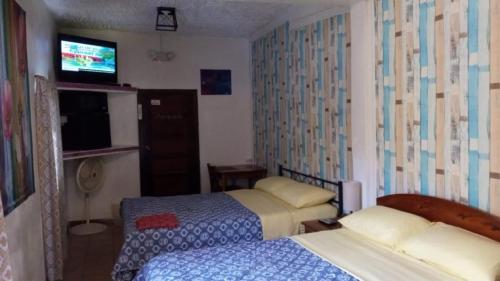a hotel room with two beds and a television at Maxroomz in San Ignacio