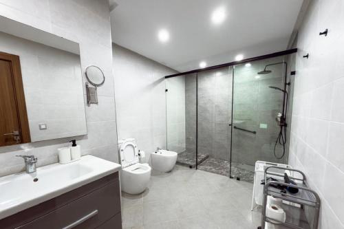 a bathroom with a shower and a toilet and a sink at Luxury Apartment with Private Patio & City Charm in Al Hoceïma