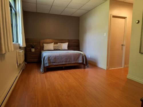 a bedroom with a bed and a wooden floor at Auberge du Mont Rigaud in Rigaud