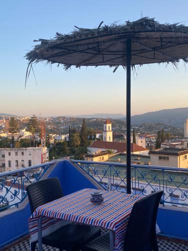 a table and chairs with an umbrella on a balcony at Hotel Al Manar in Chefchaouene