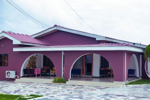 a pink house with a patio in front of it at Chez Tina Guest House and Event Centre in New Weija