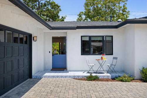 a white house with a blue door and two chairs at Mesa Breeze by Paradise Retreats in Santa Barbara
