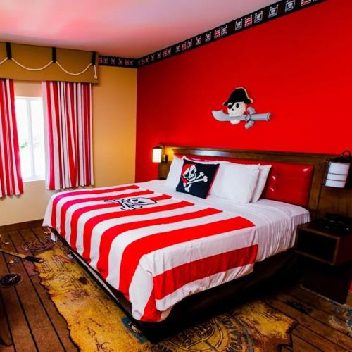 a bedroom with a bed with a red wall at LEGOLAND California Hotel and Castle Hotel in Carlsbad