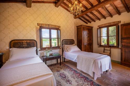 une chambre avec deux lits et un lustre dans l'établissement Podere Siliano Basso, à Castiglione del Lago