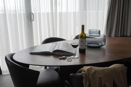 a table with a bottle of wine and a book at Parmelia Hilton Perth in Perth