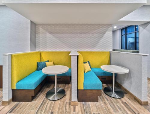 a rendering of a waiting room with yellow and blue seats and tables at Hampton Inn & Suites Omaha Un Medical Center Area in Omaha