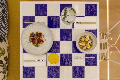 a table with plates of food on a chessboard at Amarello Hotel Praia Santo André, Tapestry Collection by Hilton in Santiago do Cacém