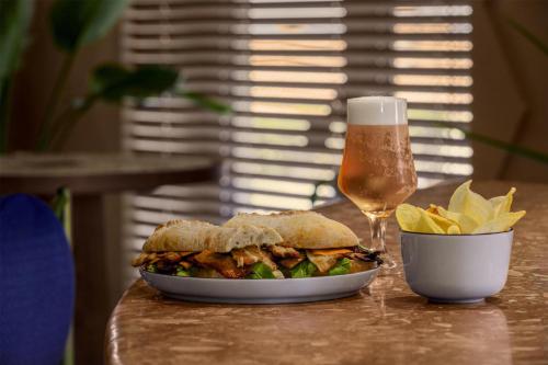 a sandwich and chips and a glass of beer on a table at Amarello Hotel Praia Santo André, Tapestry Collection by Hilton in Santiago do Cacém