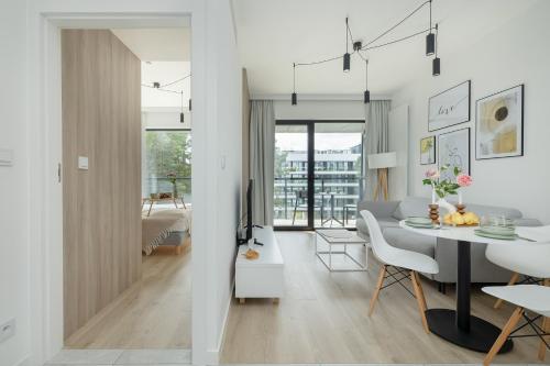 a white living room with a table and a dining room at Shelter Apartments by Solarento in Rogowo