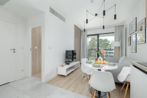 a white living room with a white table and chairs at Shelter Apartments by Solarento in Rogowo