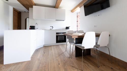a kitchen with white cabinets and a table and chairs at Morcelli 4 - Bajona in Bormio