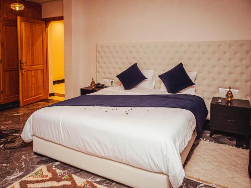 ein Schlafzimmer mit einem großen weißen Bett mit blauen Kissen in der Unterkunft Palais Dar Souhir in Aït Bou Zguia