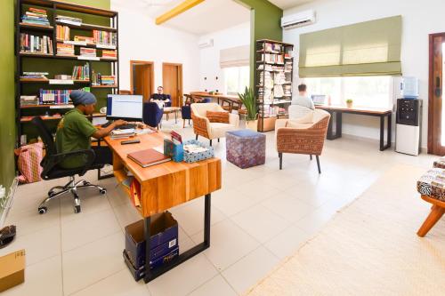 eine Person, die an einem Schreibtisch in einer Bibliothek sitzt in der Unterkunft Aura Space Apartments & Villas Fumba Town Zanzibar in Dambani