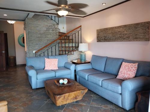 a living room with two blue couches and a table at Playa Flamingo penthouse with pacific sunset views - Flamingo Rose Vista in Playa Flamingo