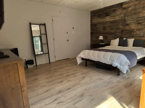 a bedroom with a bed and a wooden wall at Auberge du Mont Rigaud in Rigaud