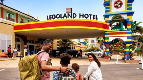 a man and two children standing in front of a hotel at LEGOLAND California Hotel and Castle Hotel in Carlsbad