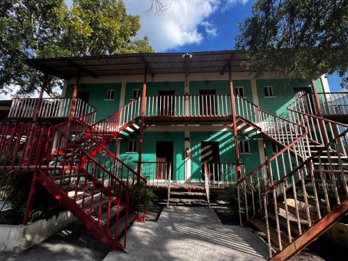 a green building with red stairs in front of it at Lamanai Hotel & Marina in Orange Walk