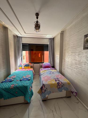 a bedroom with two beds and a window at Appartement de rêve à El Jadida, à proximité de la mer in El Jadida