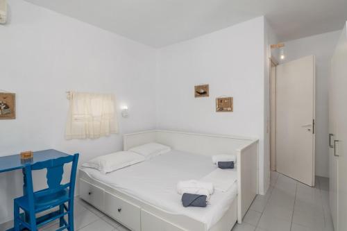 a white room with a bed and a blue chair at Paraspori in Adamantas