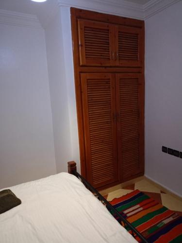 a bedroom with a bed and a wooden cabinet at Heaven Surf House Private Group Stay Sleeps 24 in Tamraght Ouzdar