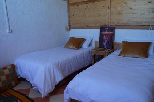 two beds in a room with white sheets at Heaven Surf House Private Group Stay Sleeps 24 in Tamraght Ouzdar