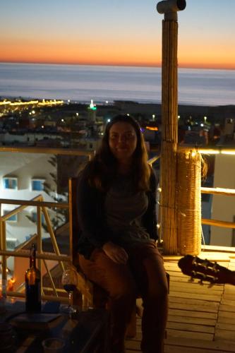 a woman sitting on top of a balcony at sunset at Heaven Surf House Private Group Stay Sleeps 24 in Tamraght Ouzdar