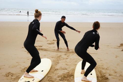 three people standing on surfboards on the beach at Heaven Surf House Private Group Stay Sleeps 24 in Tamraght Ouzdar