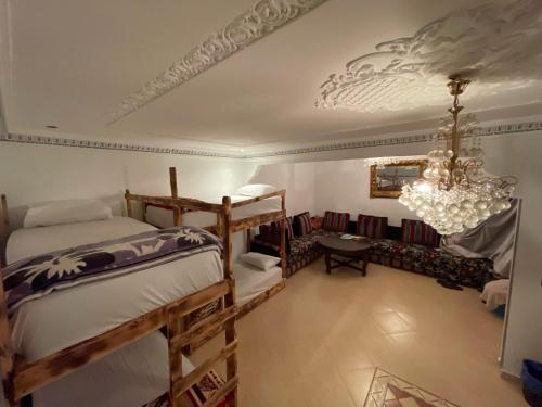 a bedroom with two bunk beds and a chandelier at Heaven Surf House Private Group Stay Sleeps 24 in Tamraght Ouzdar