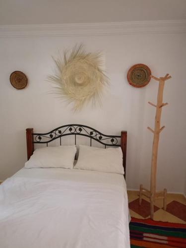 a bedroom with a bed and a cross on the wall at Heaven Surf House Private Group Stay Sleeps 24 in Tamraght Ouzdar