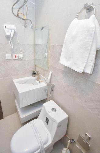 a white bathroom with a toilet and a sink at شقق برج الفخامة in Quai