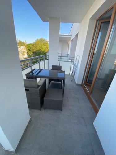 a patio with a table and chairs on a balcony at Sunny Franciszkanska Nowy apartament 4os 2 min z S6 in Koszalin