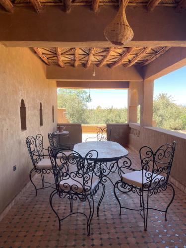 a patio with a table and chairs on a porch at Skoura Ranch Palm Grove in Ouarzazate