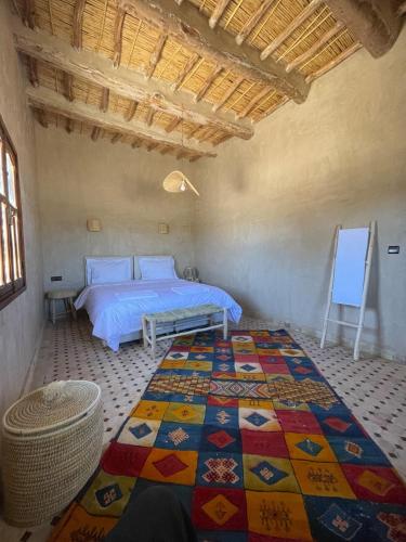 a bedroom with a bed with a colorful quilt at Skoura Ranch Palm Grove in Ouarzazate