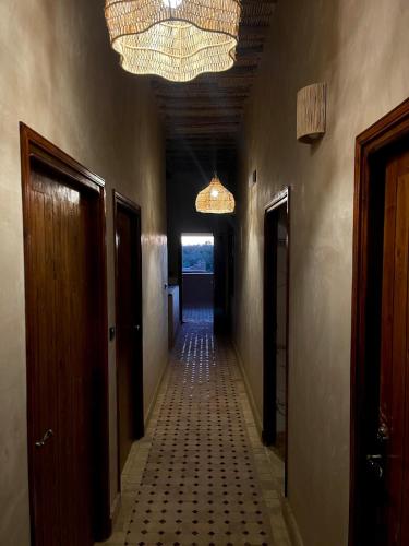 an empty hallway with a chandelier and a hallway with doors at Skoura Ranch Palm Grove in Ouarzazate