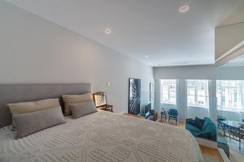 a bedroom with a large bed and some chairs at Art Living Estação by Home Sweet Home Aveiro in Aveiro