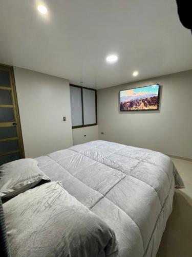a bedroom with a large bed with a tv on the wall at Apartamento Paramount in Huaraz