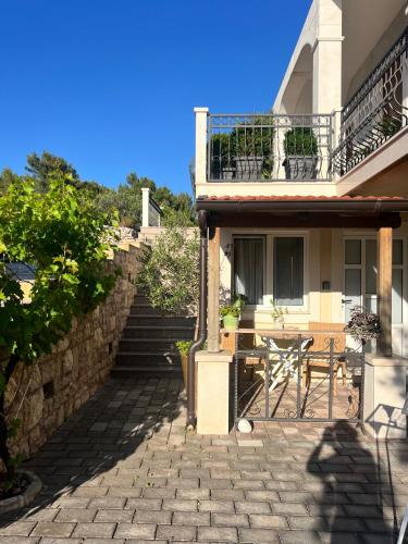 a house with a patio with a table and a balcony at Apartments Coco in Hvar