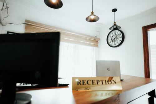a desk with a laptop and a clock on the wall at The French Square in Alleppey