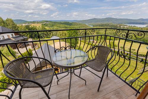 a table and chairs on a balcony with a view at Noclegi Biały Bór Widok na góry i Zalew Soliński 530-487-636 in Polańczyk
