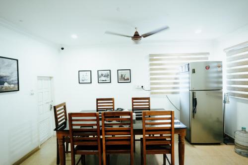 a kitchen with a table and chairs and a refrigerator at The French Square in Alleppey