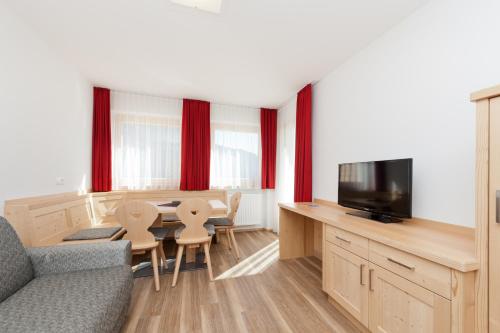 a living room with a couch and a table with a tv at Mountain Residence Montana in Santa Maddalena in Casies