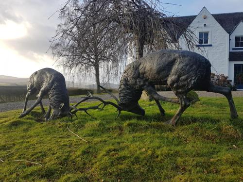 two statues of animals grazing in the grass at Fordie Lodge in Comrie