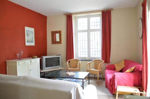 a living room with a couch and a tv at Château de la Motte in Yvoir