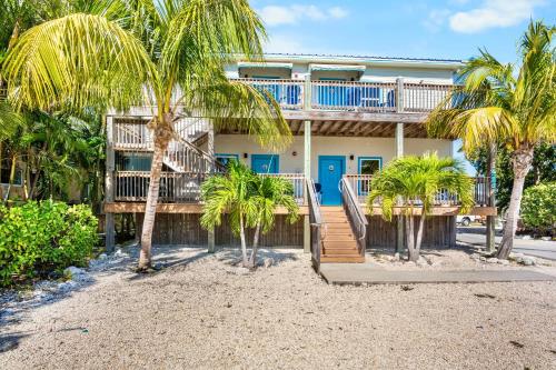 a house on the beach with palm trees in front at Coconut Cay Resort in Marathon