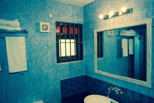 a blue bathroom with a sink and a mirror at Lar Amorosa Boutique Hotel - Goa in Calangute
