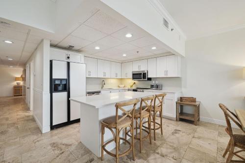 kuchnia z białymi szafkami oraz wyspa z barowymi stołkami w obiekcie HP 16W Seadawg by 30A Escapes w mieście Rosemary Beach