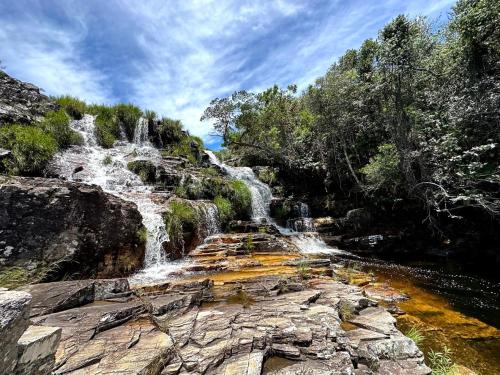 a waterfall on the side of a mountain with trees at Vale das Cachoeiras in São João Batista do Glória