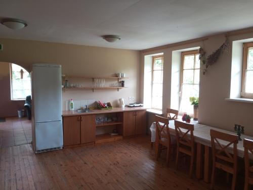 Una cocina con refrigerador y una mesa y sillas. en Viesu nams Pinka, en Alsunga