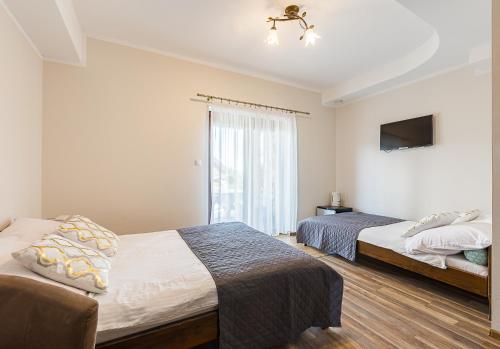 a bedroom with two beds and a television in it at Noclegi Biały Bór Widok na góry i Zalew Soliński 530-487-636 in Polańczyk