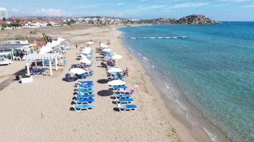 a beach with chairs and umbrellas and the ocean at Апартаменты в комплексах Цезарь Бич и Цезарь Блю in Boğaz